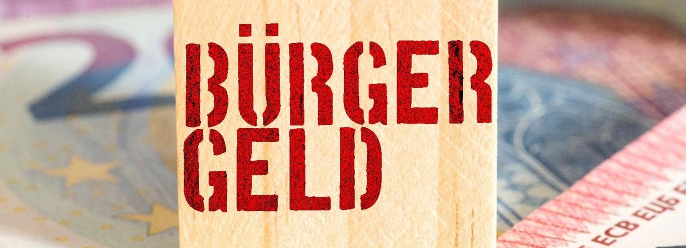 Ein Foto zeigt einen Holzwürfel mit dem Schriftzug "Bürgergeld", der auf Euro-Geldscheinen liegt.
