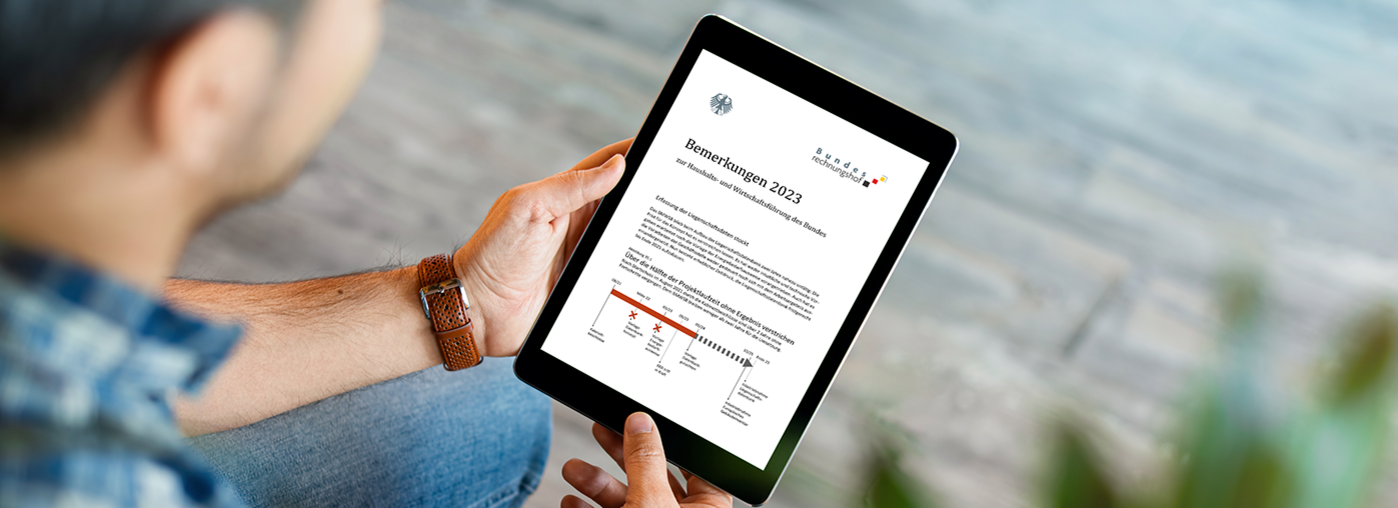 Ein von einem Mann gehaltenes Tablet zeigt einen Ausschnitt aus dem Ergänzungsband der Bemerkungen 2023 des Bundesrechnungshofes.