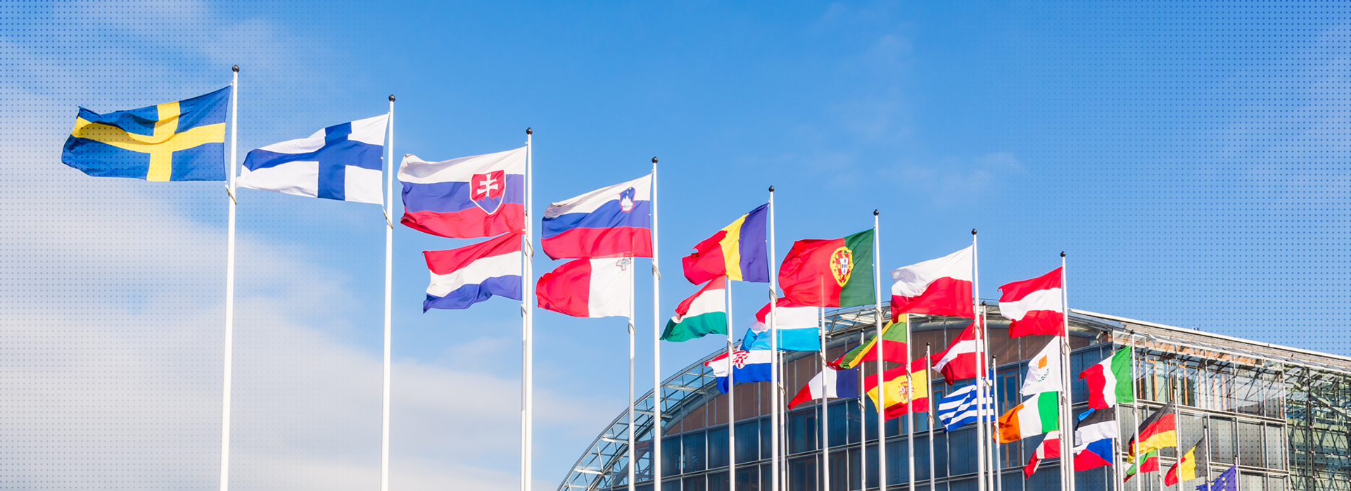 Das Bild zeigt die Flaggen der EU-Mitgliedsstaaten an Masten vor einem klaren blauen Himmel.