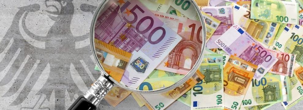 Das Foto zeigt einen losen Haufen an verschiedenen Euro-Geldscheinen. Eine Lupe vergr&ouml;&szlig;ert einige Scheine. Neben den Geldscheinen ist der Bundesadler auf grauen Beton gemalt. Montage: Bundesrechnungshof