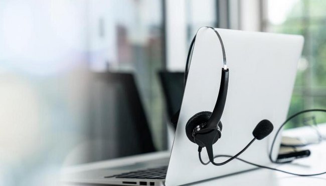 Servicestelle des Bundesbeauftragten für Wirtschaftlichkeit in der Verwaltung Ein aufgeklapptes Notebook. Über der Kante vom Bildschirm hängt lose ein Headset.