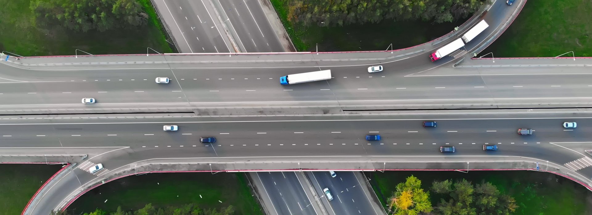 Zu sehen sind Autos auf zwei mehrspurigen Stra&szlig;en, die sich mittels einer Br&uuml;cke kreuzen.