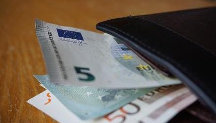 Das Foto zeigt eine schwarze Gedlb&ouml;rse mit verschiedenen Euro-Banknoten darin, die auf einem Holztisch liegt.