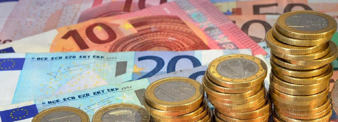 Euroscheine und Euromünzen liegen verteilt auf einem Tisch.